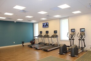 A fitness room with treadmills and elliptical machines, wooden flooring, and a large window. - Holiday Inn Express Athens by IHG (Athens)