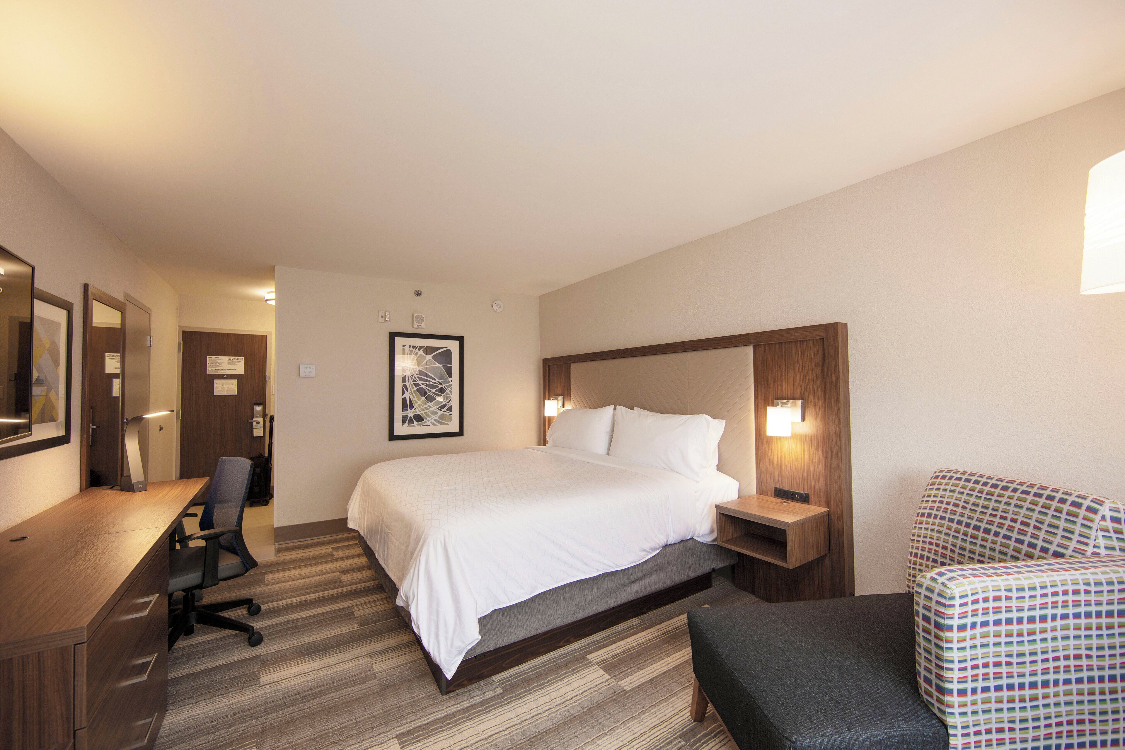 Una habitación de hotel con cama, escritorio, silla y una mesita.