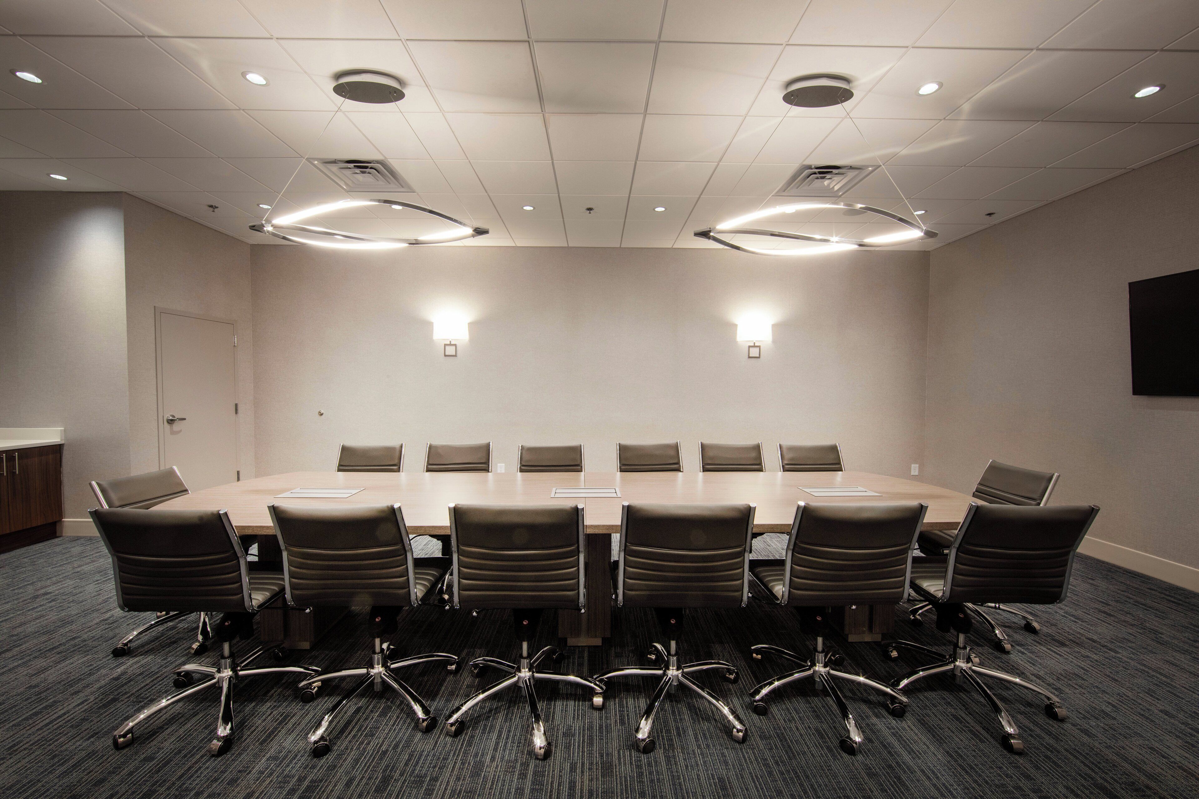 Une salle de conférence avec une longue table, de nombreuses chaises et un éclairage au plafond.