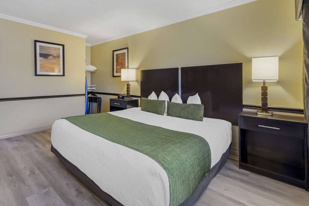A hotel room with a large bed, two bedside tables with lamps, and two wall-mounted picture frames.