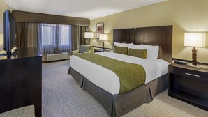 A hotel room with a large bed, two bedside tables with lamps, a desk with a chair, a flat-screen TV, and a large window with curtains. - Best Western Canoga Park Motor Inn (Winnetka)