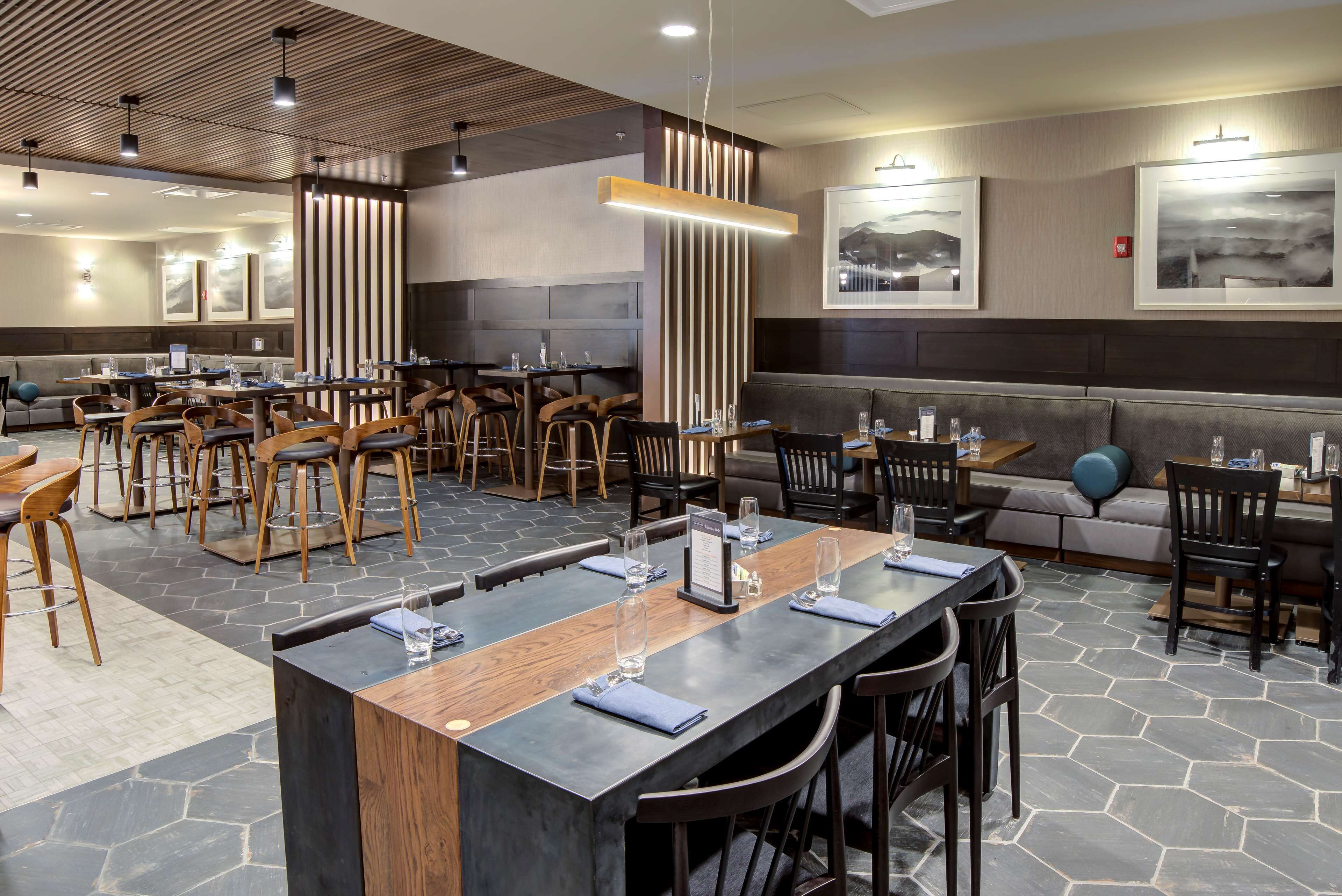 A modern restaurant with a long communal table, booths, and high chairs.