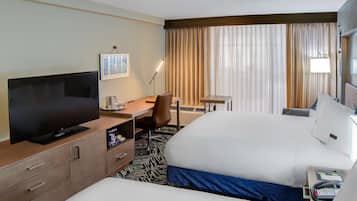 Una habitación de hotel con una cama grande, un escritorio con una silla, un televisor y una mesita.