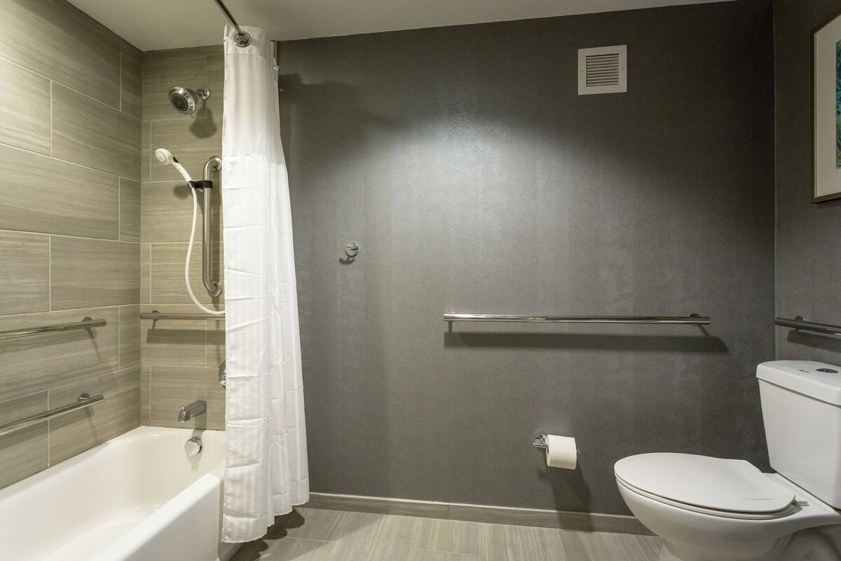 A bathroom with a bathtub, shower, toilet, and a towel rack.