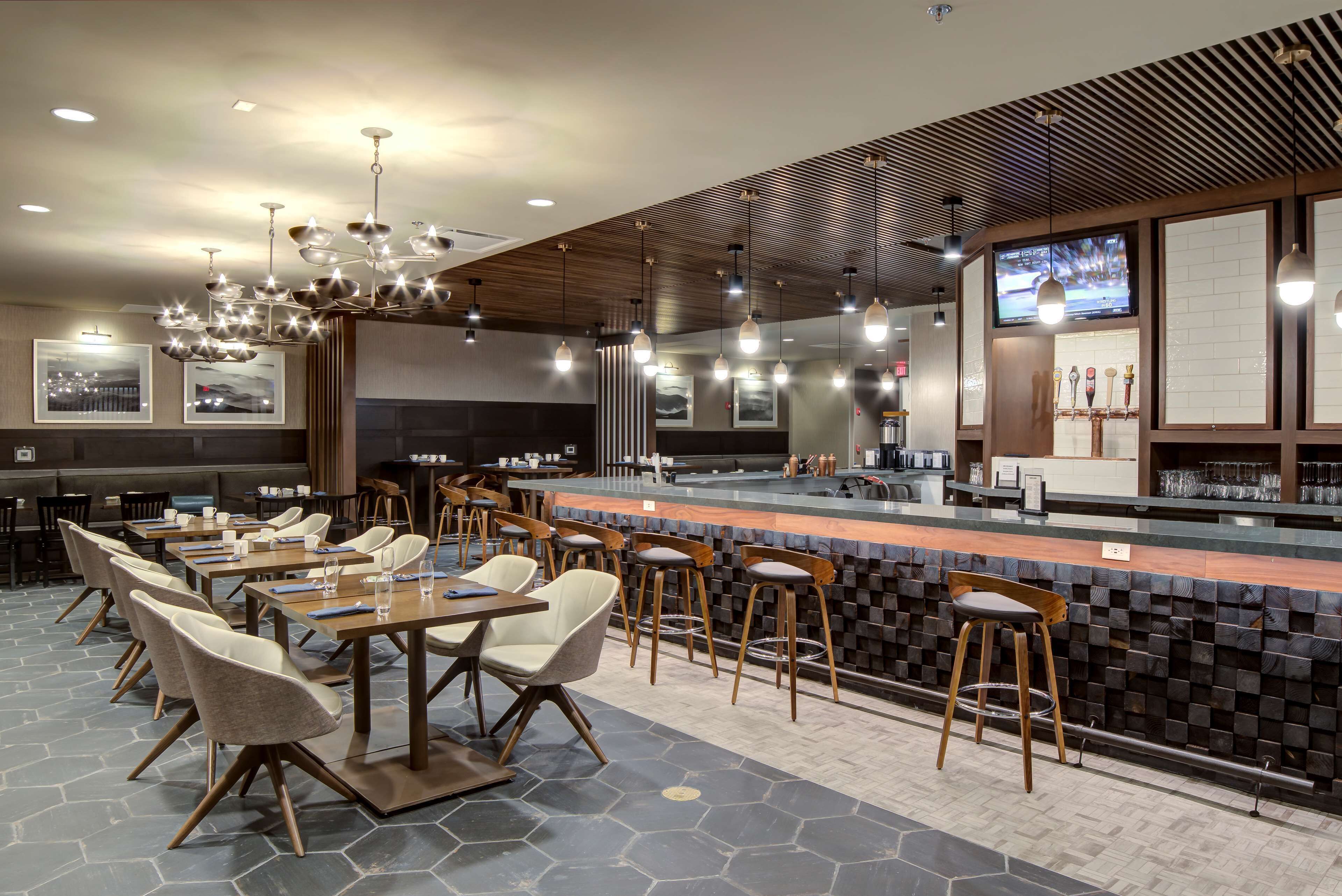 Un restaurante moderno con barra, suelo de baldosas hexagonales y mobiliario contemporáneo.