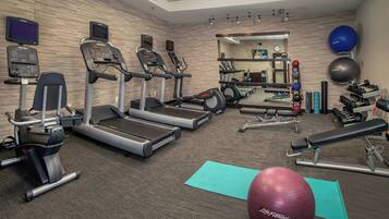 A gym with treadmills, elliptical machines, a bench press, and exercise balls.