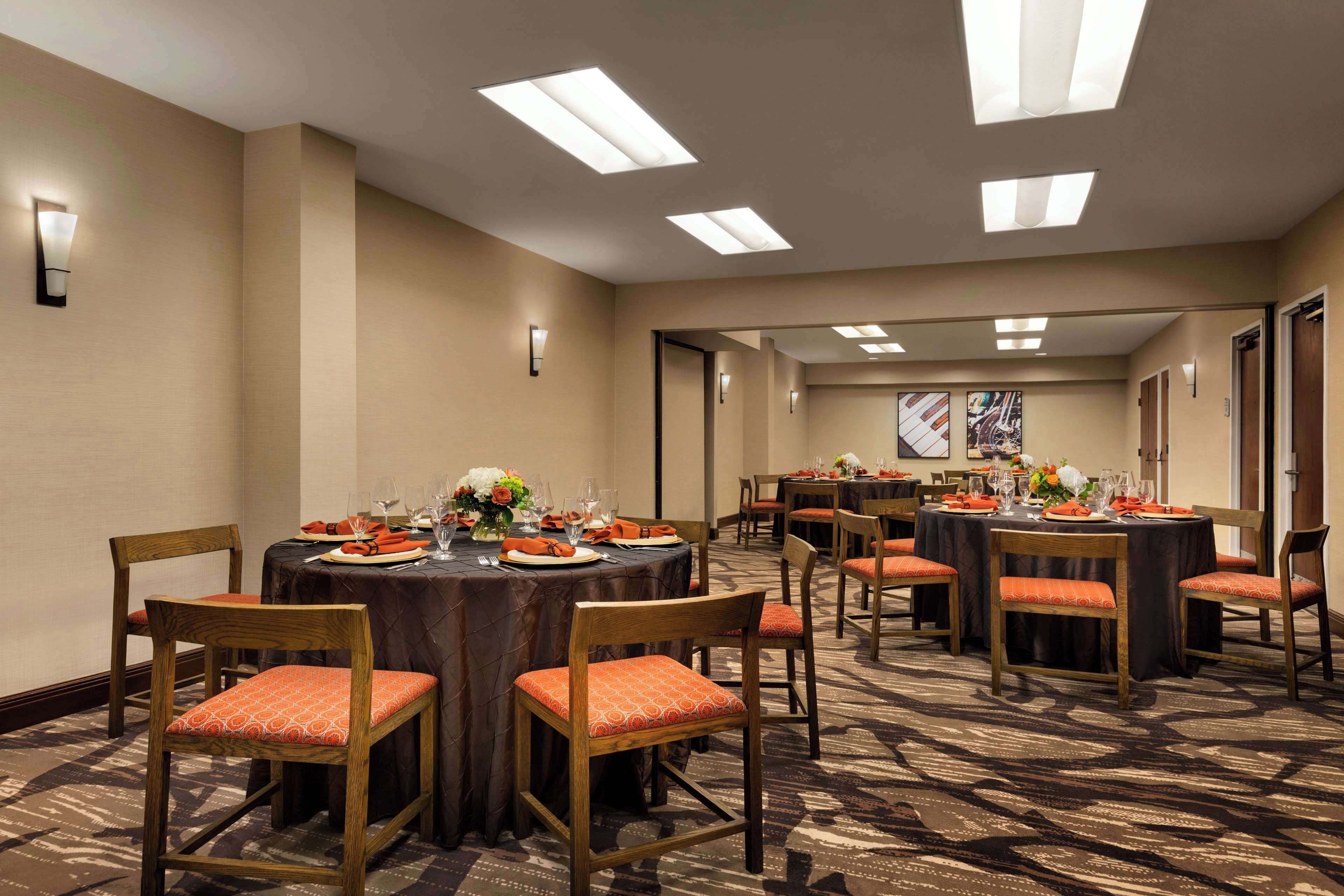 A conference room with multiple tables, chairs, and overhead lighting.