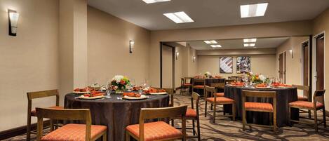 A conference room with multiple tables, chairs, and overhead lighting.