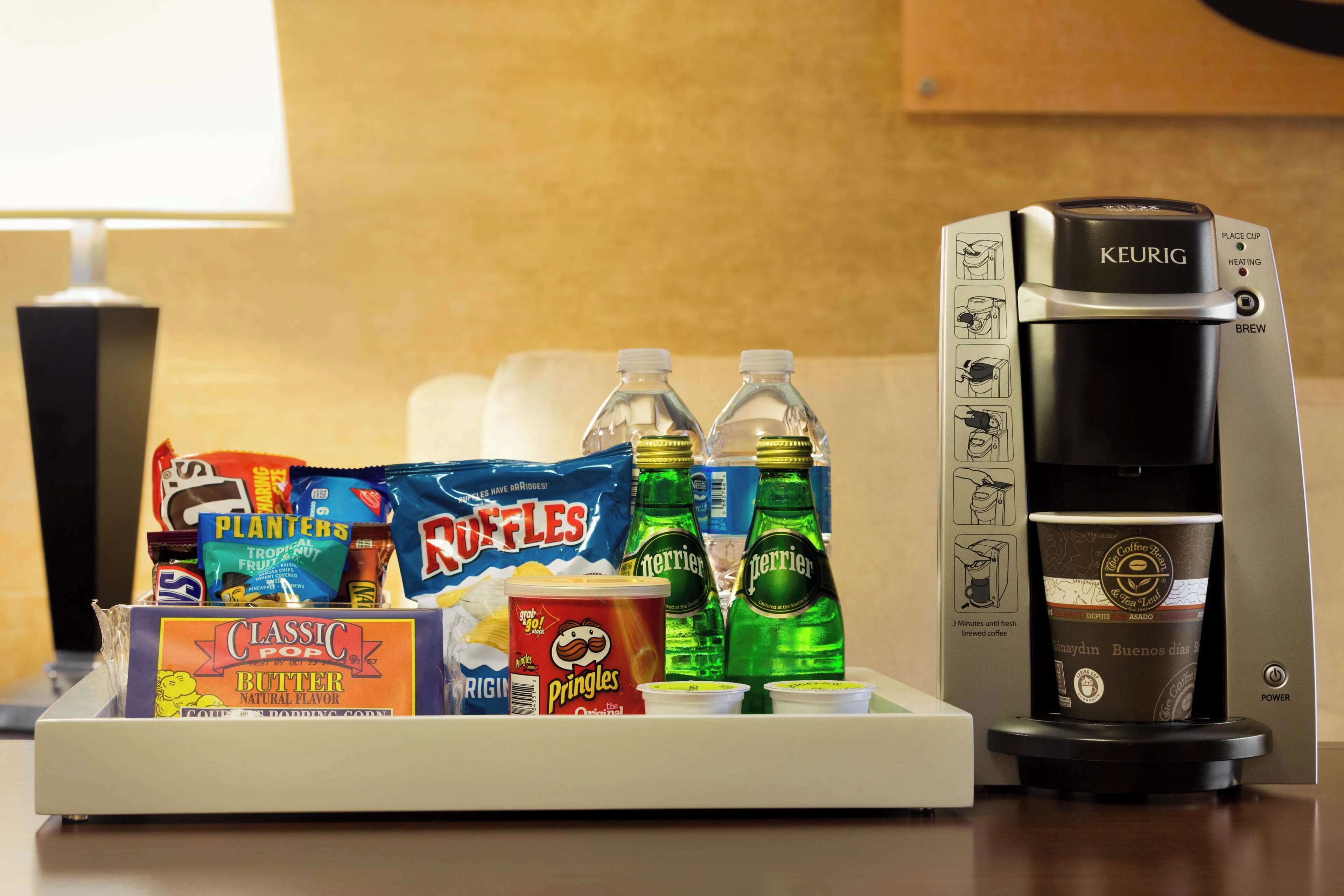 A coffee maker, snacks, and drinks on a table.