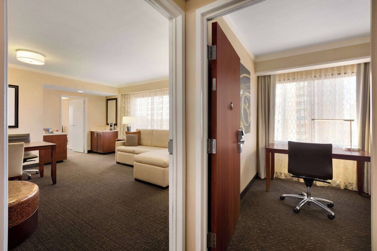 A hotel room with a bed, a desk, a chair, a sofa, and a small table.