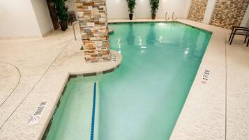 Swim laps in the pool surrounded by a seating area and lush greenery.