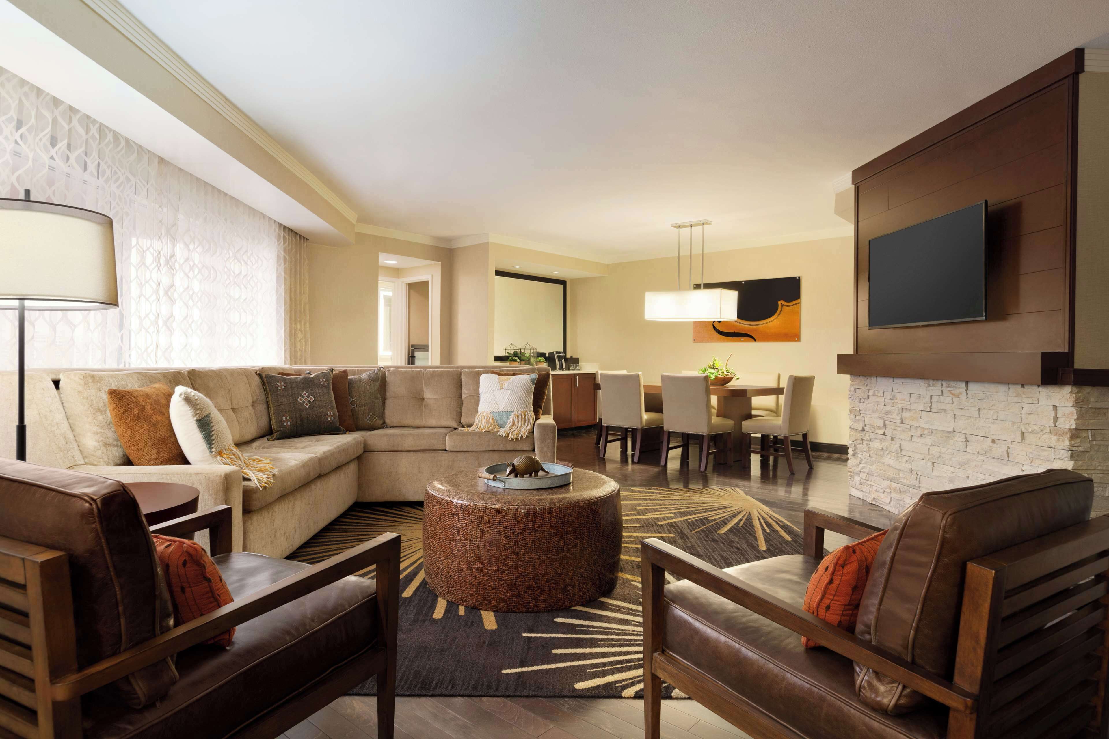 A modern living room with a sectional sofa, a round coffee table, and a fireplace.