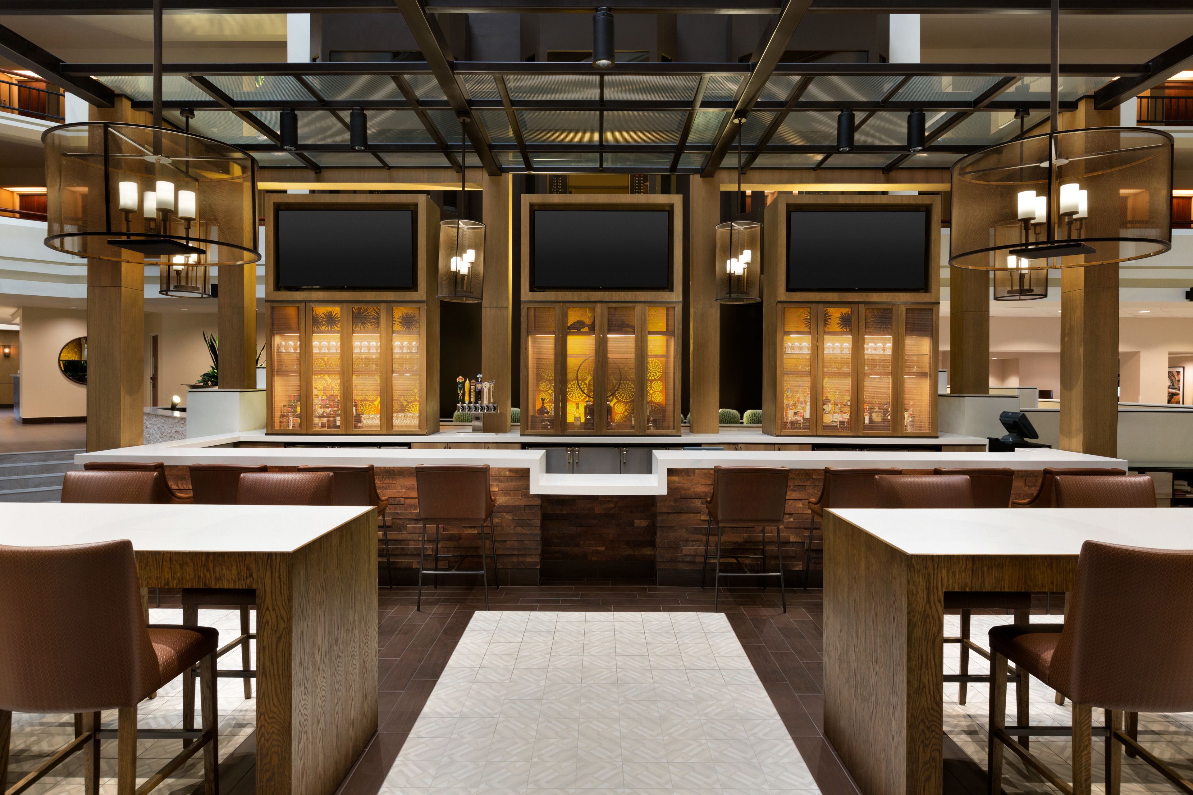 A modern bar area with a central counter, multiple seating options, and a large screen.