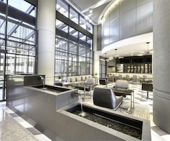A modern lobby with a central water feature, seating area, and a bar.