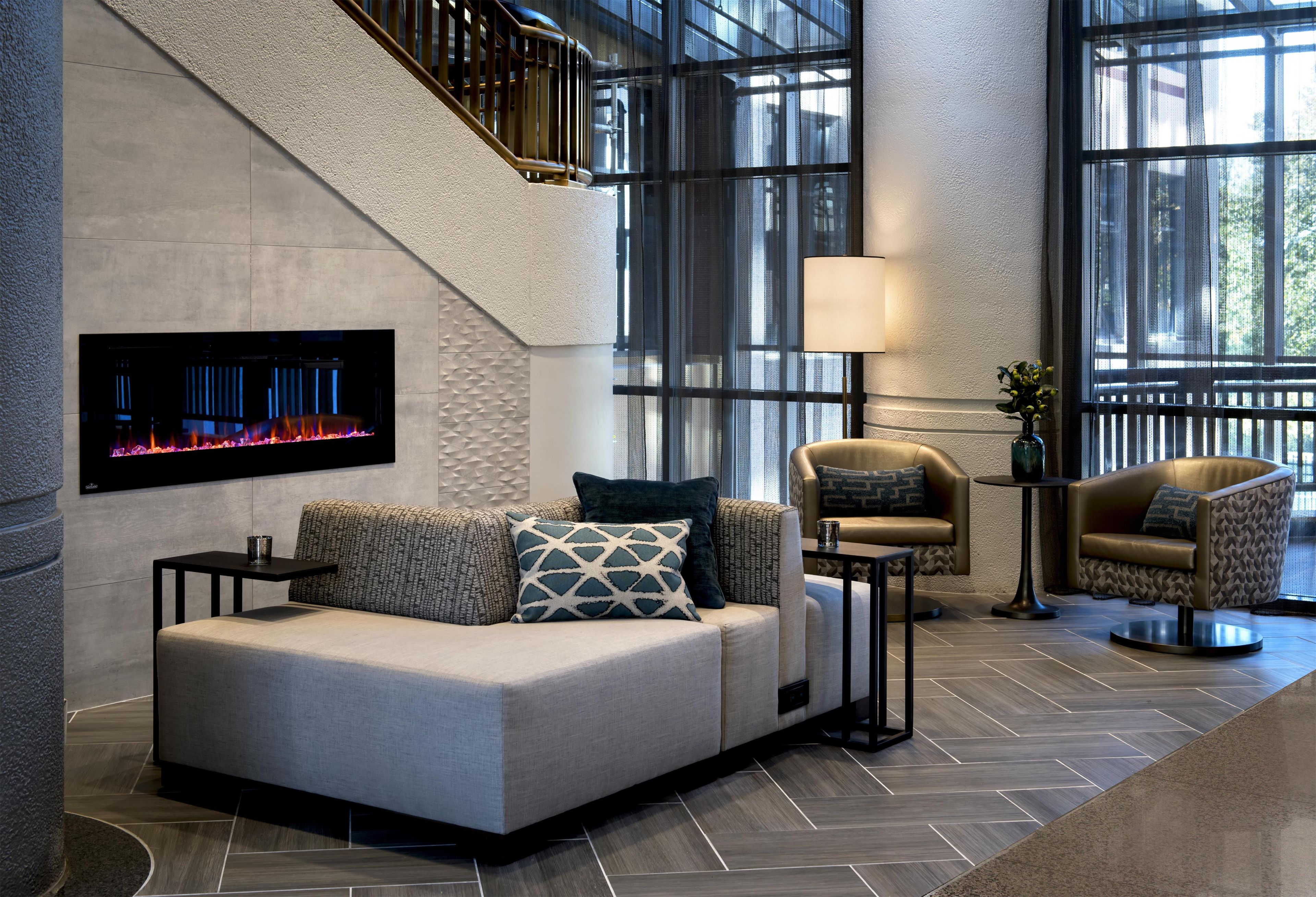 A modern interior with a sofa, armchairs, a fireplace, and a staircase.