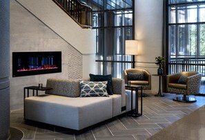 A modern interior with a sofa, armchairs, a fireplace, and a staircase. - Embassy Suites by Hilton Bethesda Washington DC (Bethesda)