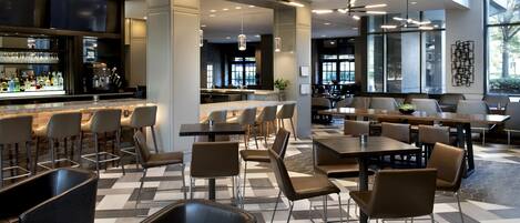 Un restaurante moderno con zona de bar, varias opciones de asientos como cabinas y mesas, y un suelo con diseño.