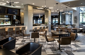 A modern restaurant with a bar area, multiple seating options including booths and tables, and a patterned floor. - Embassy Suites by Hilton Bethesda Washington DC (Bethesda)