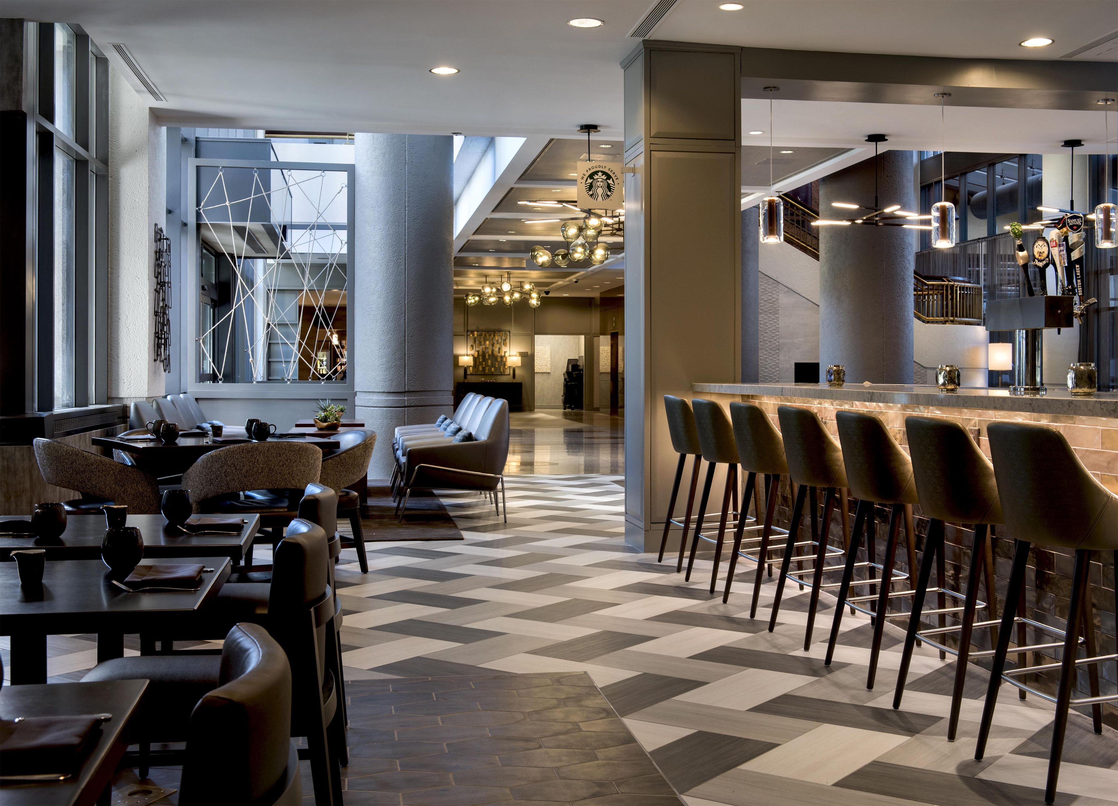 Un moderno vestíbulo de hotel con zona de bar, asientos y mostrador de recepción.