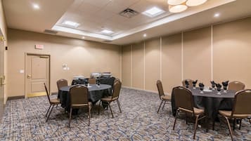 A conference room with round tables, chairs, and a carpeted floor.
