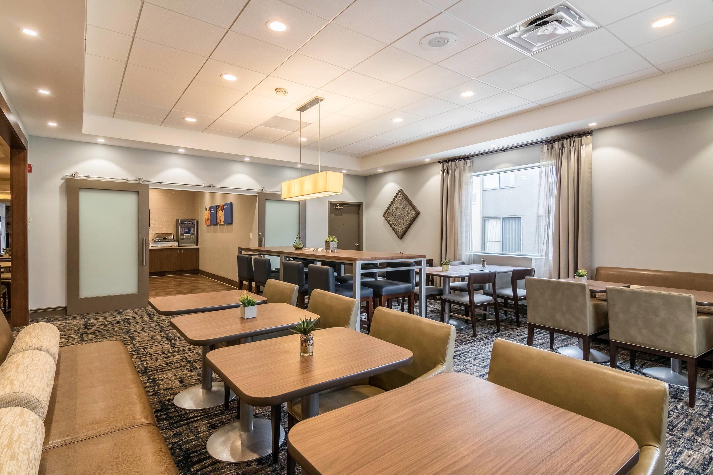 A hotel room with a dining area, a sofa, and a kitchen in the background.
