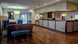 A reception area with a wooden reception desk, a sofa, and a bench. - Comfort Inn Plymouth - Minneapolis (Plymouth)
