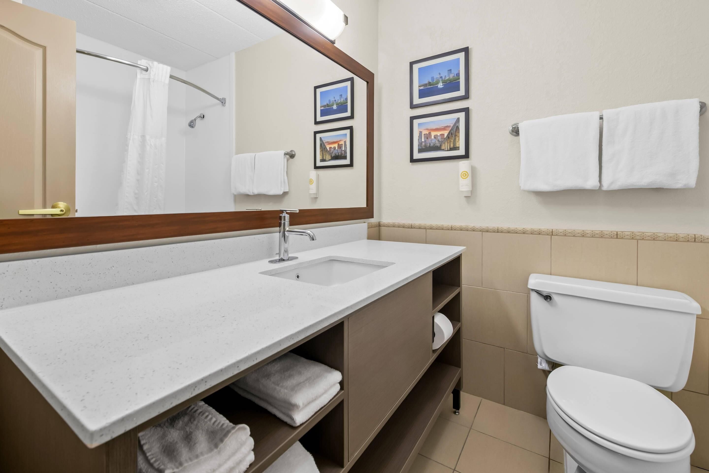 A bathroom with a sink, mirror, toilet, and towel rack.