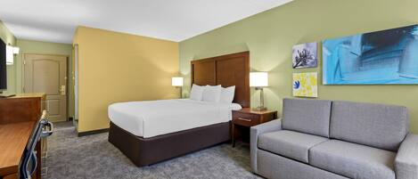 Una habitación de hotel con una cama, un sofá, un escritorio y dos lámparas de pared.