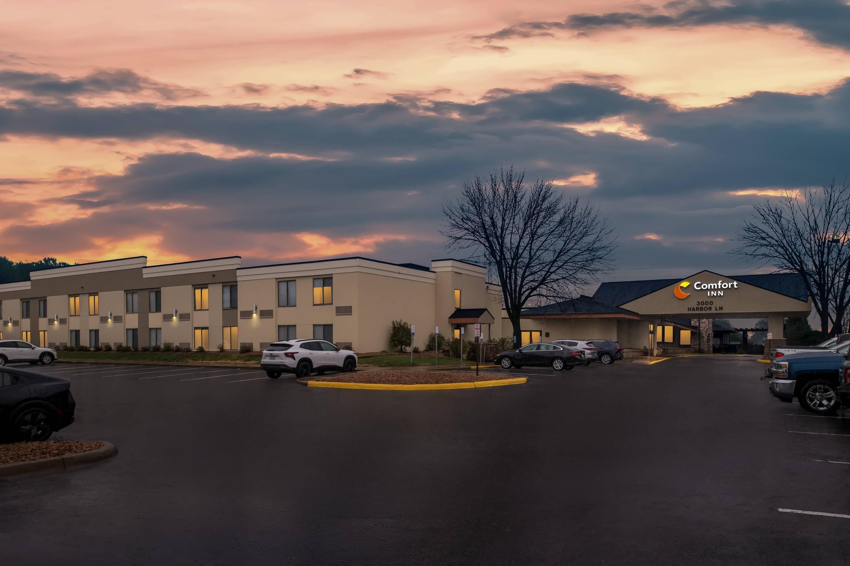 Ein Hotel mit Parkplatz, ein Gebäude mit der Beschilderung Comfort Inn und ein Sonnenuntergangshimmel.