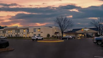 Ein Hotel mit Parkplatz, ein Gebäude mit der Beschilderung Comfort Inn und ein Sonnenuntergangshimmel.
