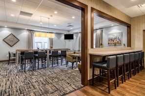 A hotel lobby with a bar area, seating arrangements, a television, and a cityscape painting. - Comfort Inn Plymouth - Minneapolis (Plymouth)