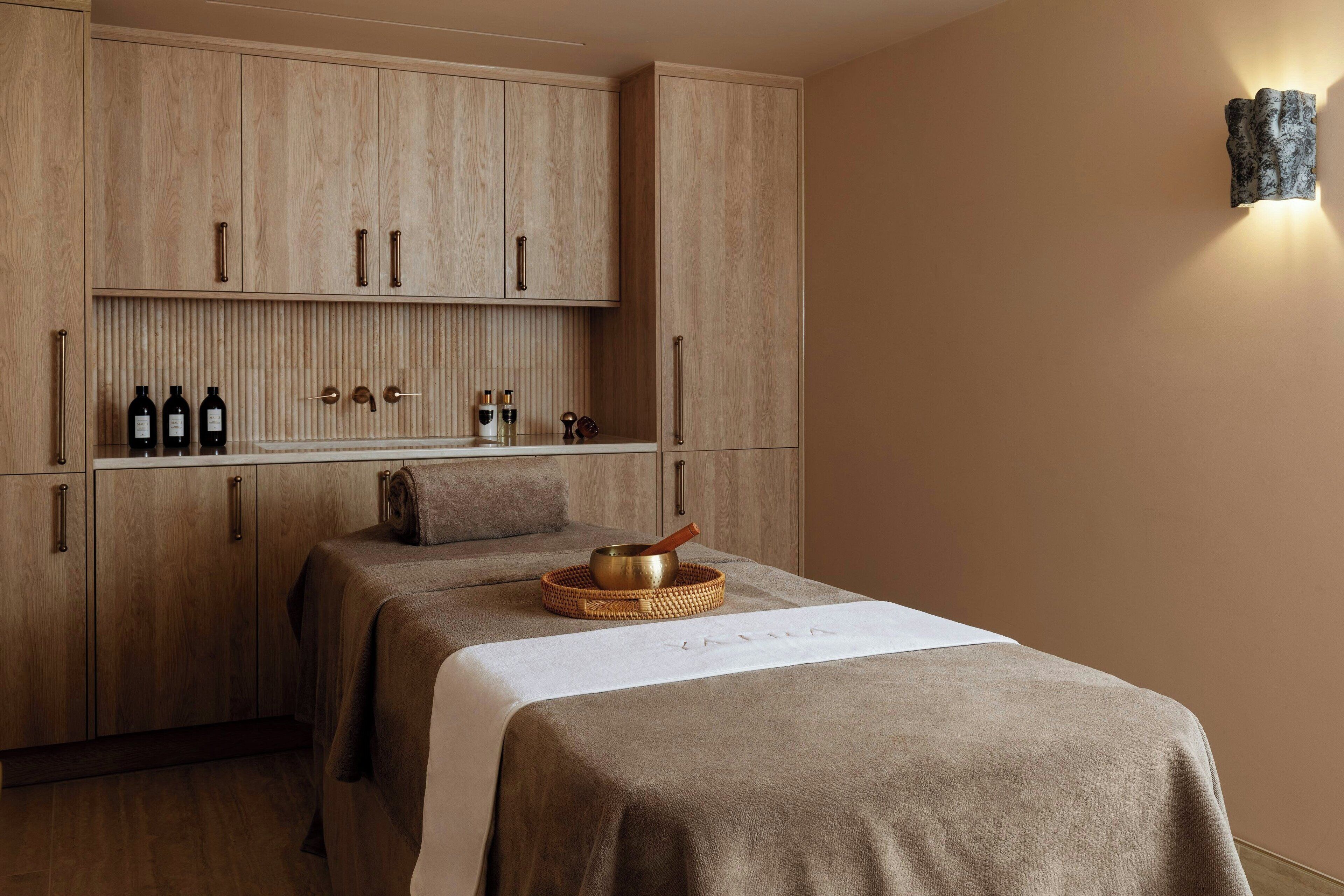 Ett spa-rum med träskåp, en massagebänk och en väggmonterad lampa.