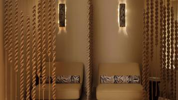 Una habitación con dos sofás, cada uno con cojines estampados, y una lámpara fijada a la pared.