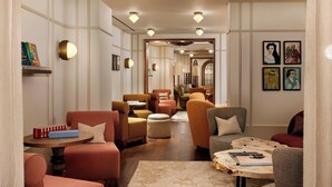 A modern hotel lobby with plush seating, a central coffee table, and artwork on the walls. - Montcalm Mayfair, Autograph Collection (London)
