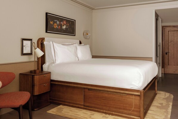 A neatly arranged bedroom with a wooden bed, a bedside table with a lamp, and a chair. - Montcalm Mayfair, Autograph Collection (London)