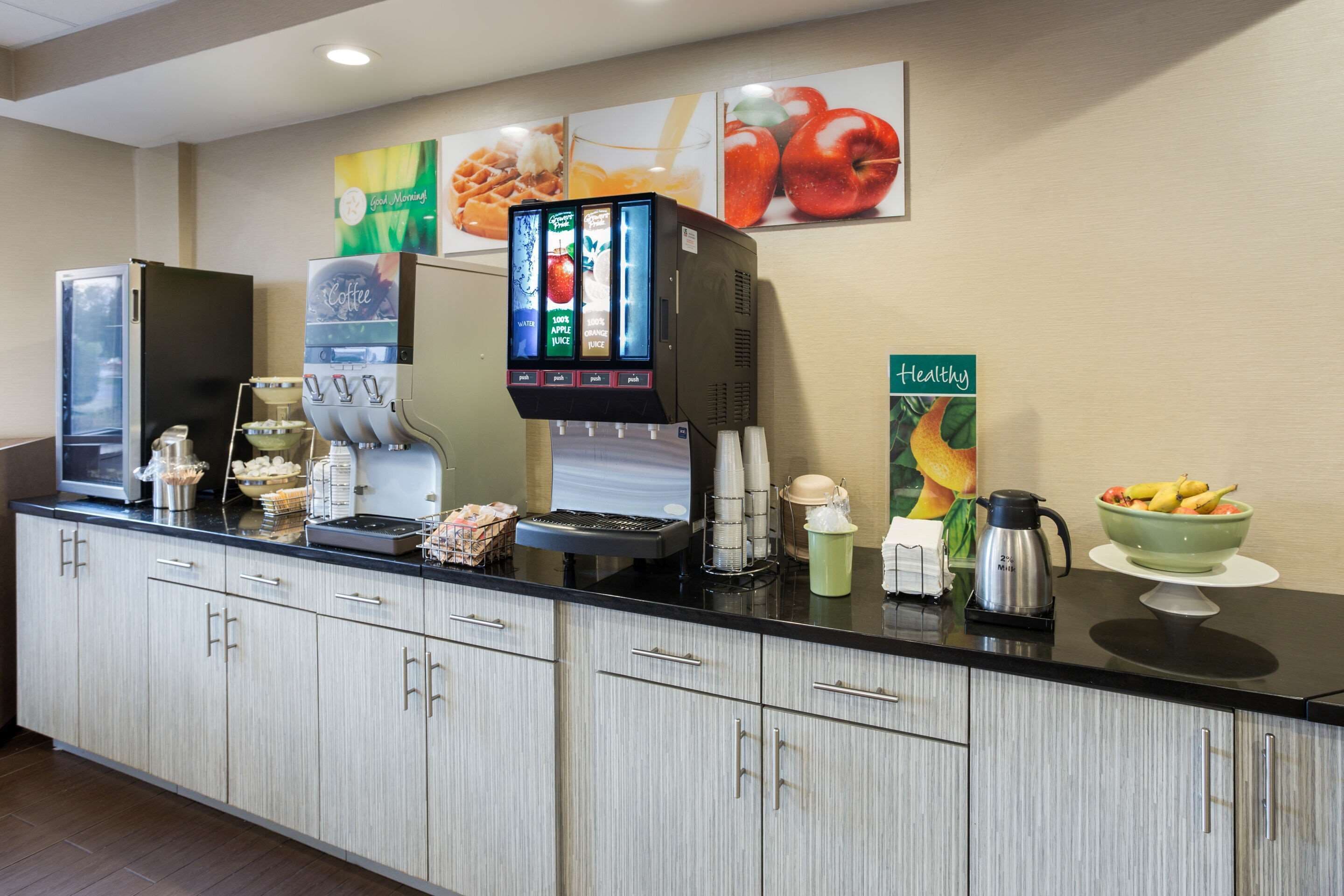 A hotel reception area with a coffee machine, a fruit bowl, and a coffee station.