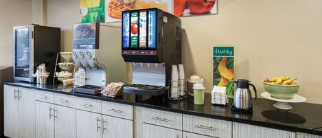 A hotel reception area with a coffee machine, a fruit bowl, and a coffee station.