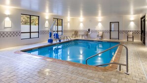An indoor swimming pool with a tiled floor, poolside chairs, and wall-mounted lights. - Quality Inn Albany Colonie (Albany)