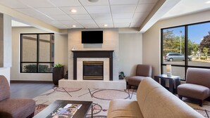 A modern lobby with a fireplace, comfortable seating, and large windows offering a view of the street. - Quality Inn Albany Colonie (Albany)