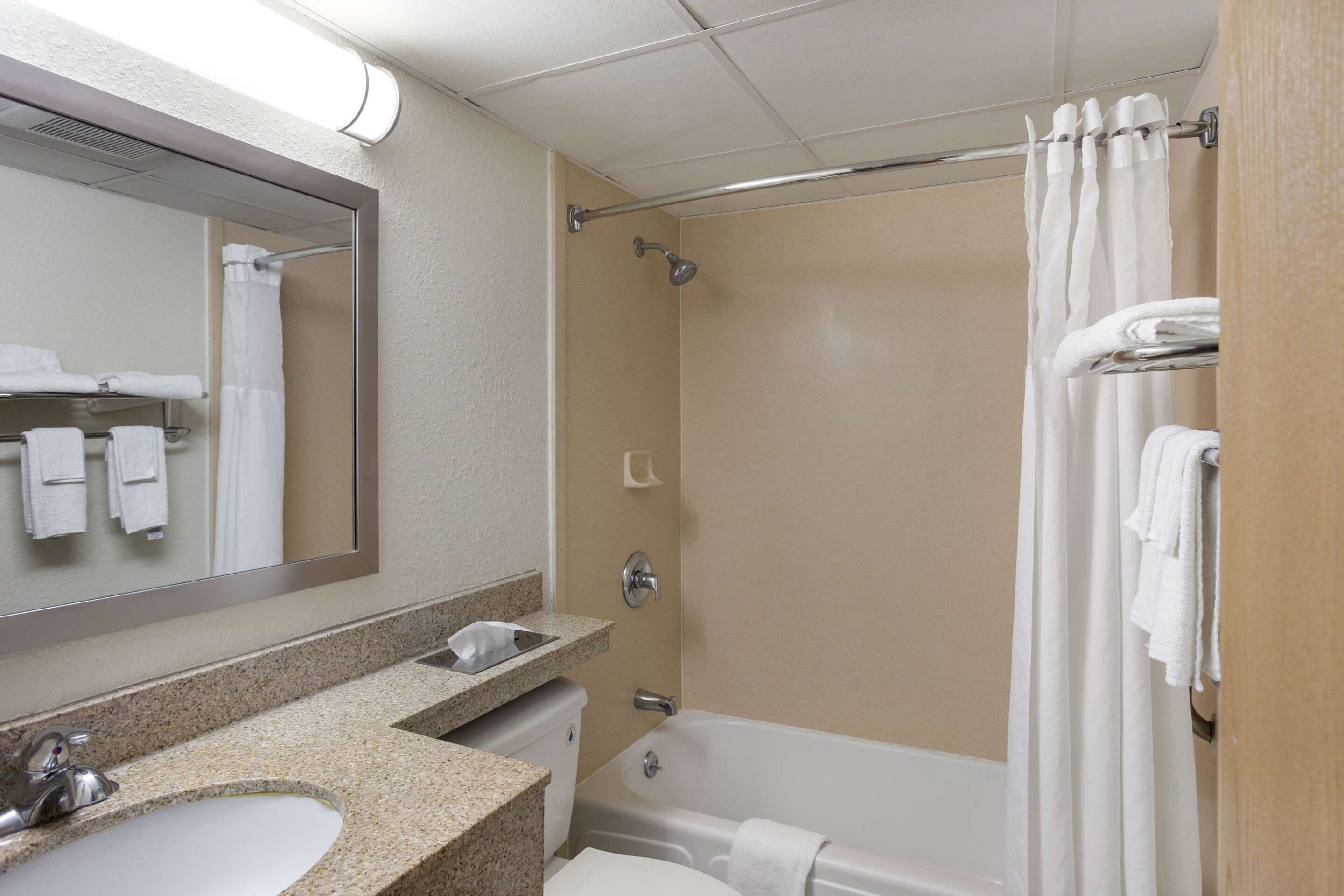 A bathroom with a sink, mirror, shower, and towel rack.