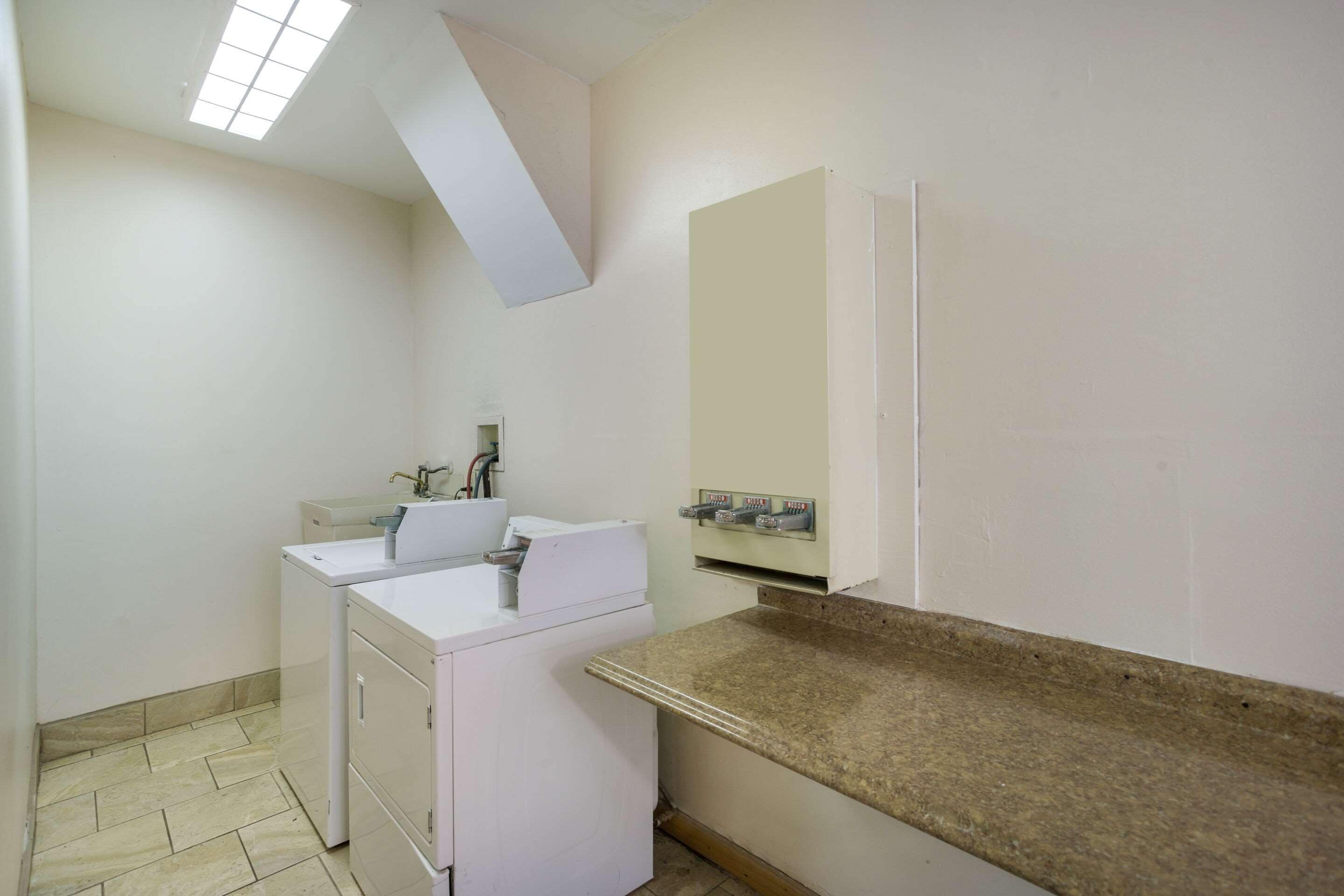 Een kleine, schone badkamer met een witte wastafel, een spiegel en een handdoekhouder.