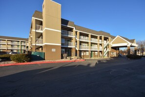 A multi-story hotel with balconies, a parking lot, and a clear sky. - HomeTowne Studios by Red Roof Denver - Lakewood West (Lakewood)