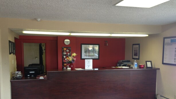 A reception desk with a clock, framed pictures, and a vase with flowers.