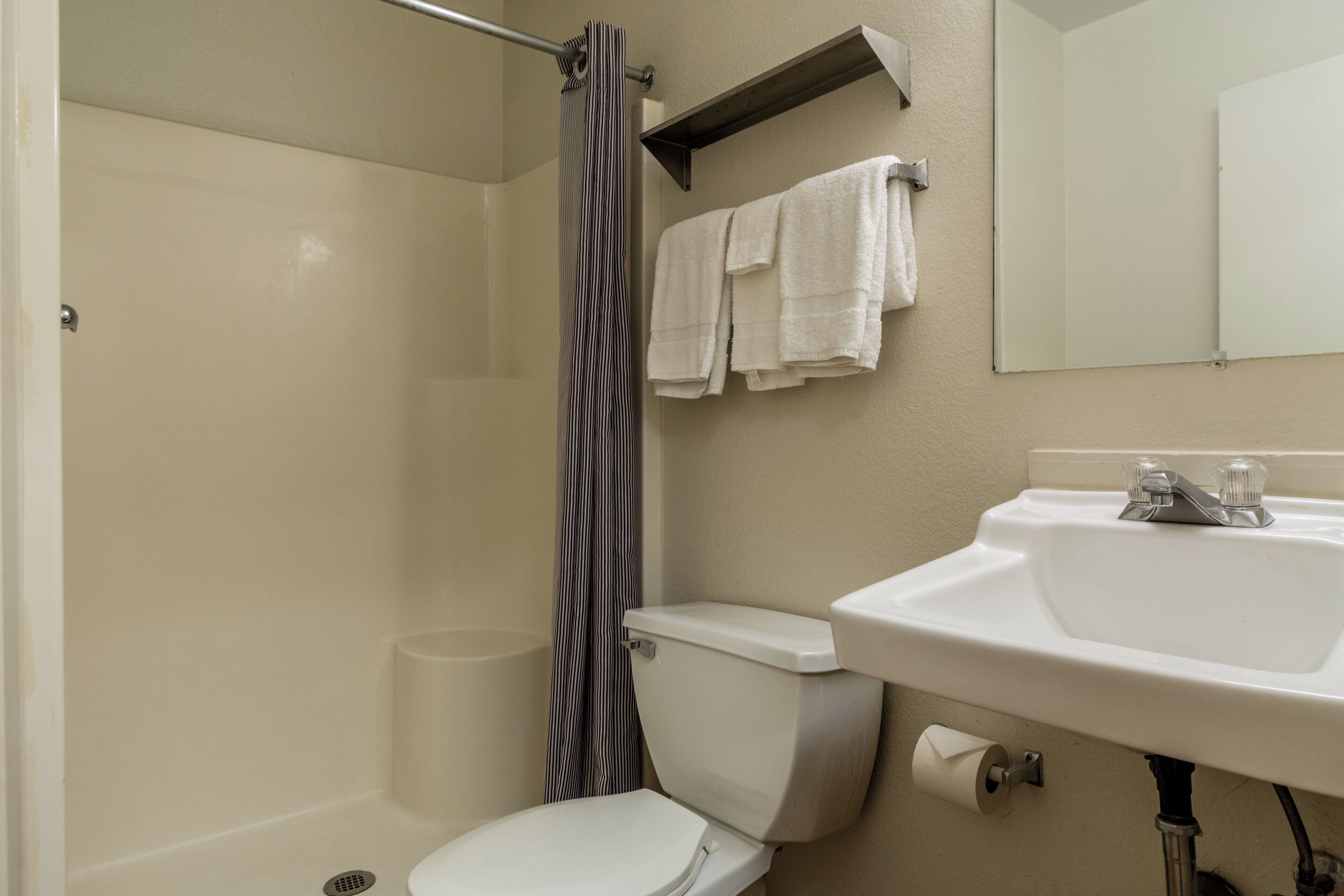 A bathroom with a toilet, a sink, a shower curtain, and a towel rack.