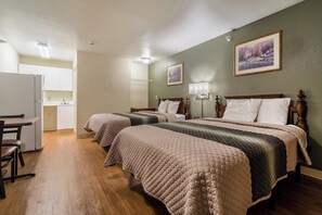 Una habitación de hotel con dos camas, un escritorio y una kitchenette.