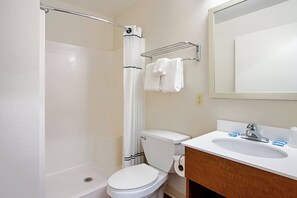 Un baño con ducha, inodoro, lavabo y espejo.