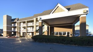 A multi-story hotel with a central atrium, balconies, and a parking lot.
