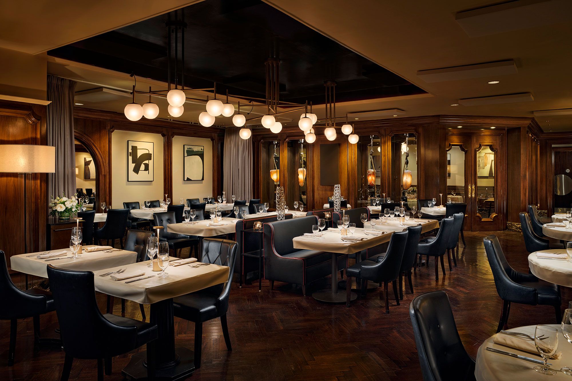 Interior de restaurante con varias mesas, sillas y lámparas colgantes.