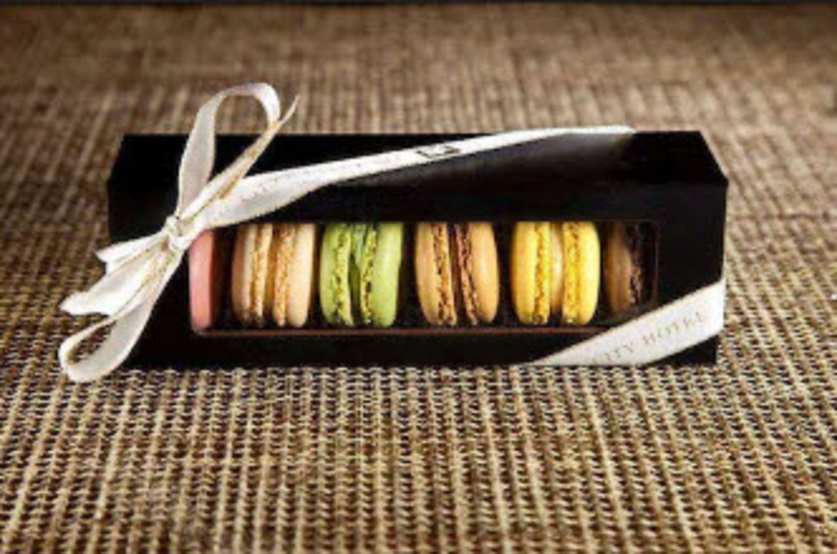 Een doosje kleurrijke macarons, vastgebonden met een lint.