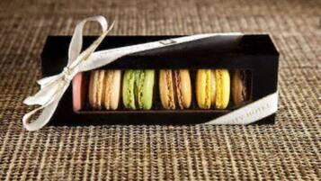 Een doosje kleurrijke macarons, vastgebonden met een lint.